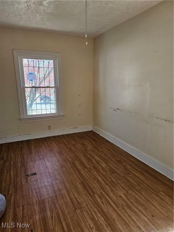 unfurnished room with baseboards, a textured ceiling, and wood finished floors