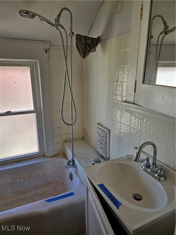 full bathroom featuring plenty of natural light, vanity, backsplash, and tile walls