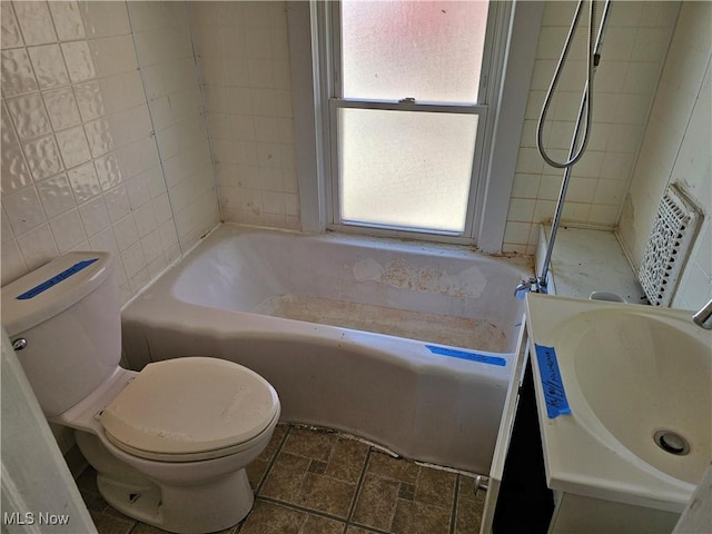 full bathroom with walk in shower, a sink, toilet, stone finish floor, and a tub to relax in