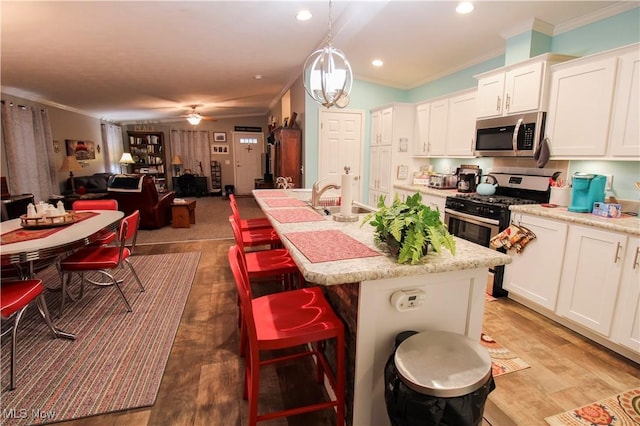 kitchen featuring crown molding, ceiling fan, white cabinetry, light wood finished floors, and stainless steel appliances