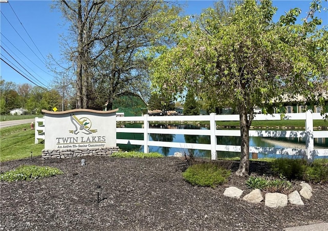 community / neighborhood sign featuring fence and a water view