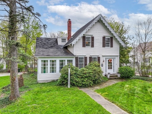 view of front of property featuring a chimney, roof with shingles, and a front yard