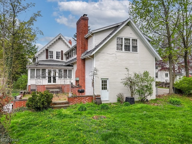 rear view of property with a lawn, a patio area, central AC, and a chimney