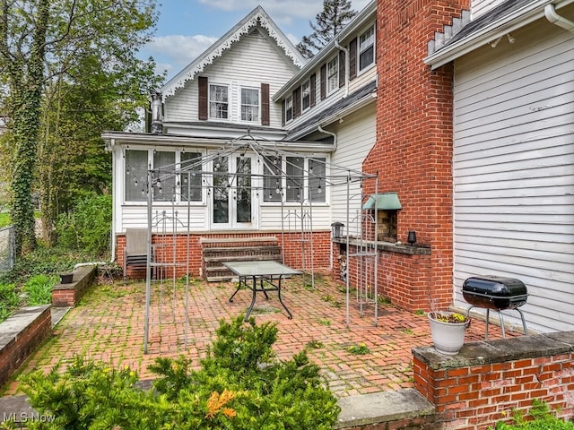 back of property with entry steps, a sunroom, and a patio area