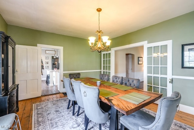 dining room featuring wood-type flooring and an inviting chandelier