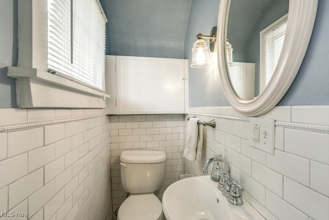 half bathroom with plenty of natural light, a wainscoted wall, and toilet