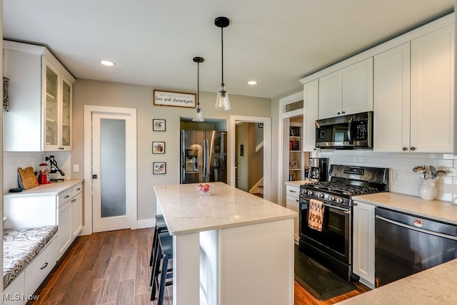 kitchen with white cabinets, stainless steel appliances, tasteful backsplash, and a center island