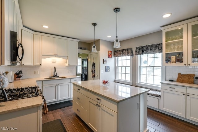 kitchen featuring white cabinetry, stainless steel microwave, decorative backsplash, and a sink