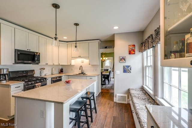 kitchen featuring visible vents, decorative backsplash, dishwashing machine, stainless steel gas range, and a sink