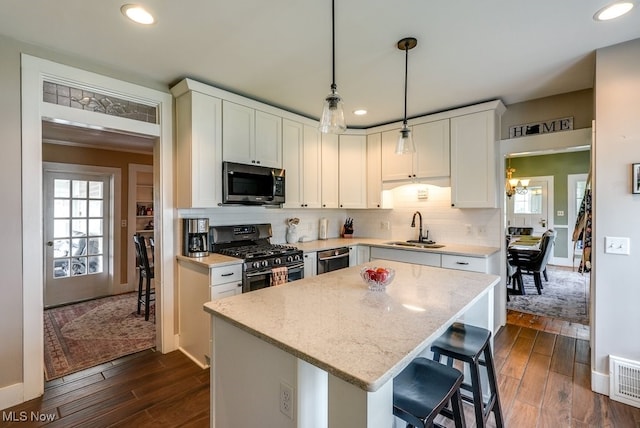 kitchen featuring appliances with stainless steel finishes, a center island, dark wood finished floors, a sink, and white cabinets