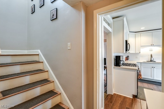 staircase with recessed lighting and wood finished floors