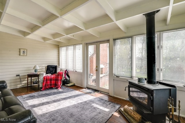 living room featuring wood-type flooring, beam ceiling, a wood stove, and coffered ceiling