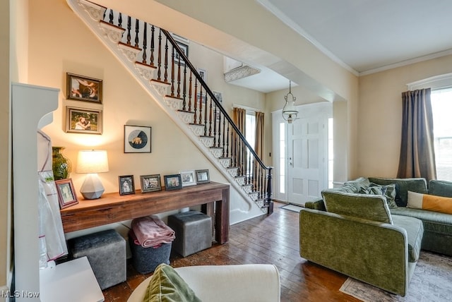 entryway with ornamental molding, wood-type flooring, and stairs