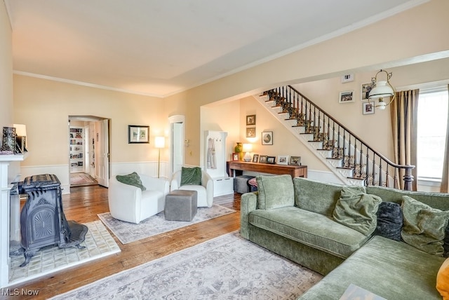 living area featuring crown molding, wood finished floors, and stairway