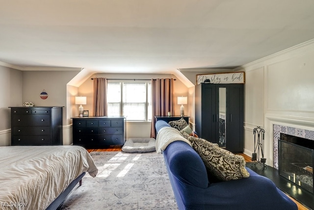 bedroom with crown molding, a fireplace, and wood finished floors