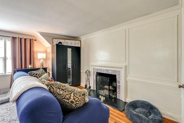 living area featuring crown molding, wood finished floors, and a tile fireplace