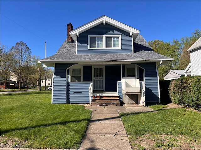 bungalow featuring covered porch, a chimney, a shingled roof, and a front lawn