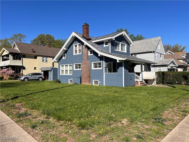 view of side of home featuring a lawn, a chimney, and a porch