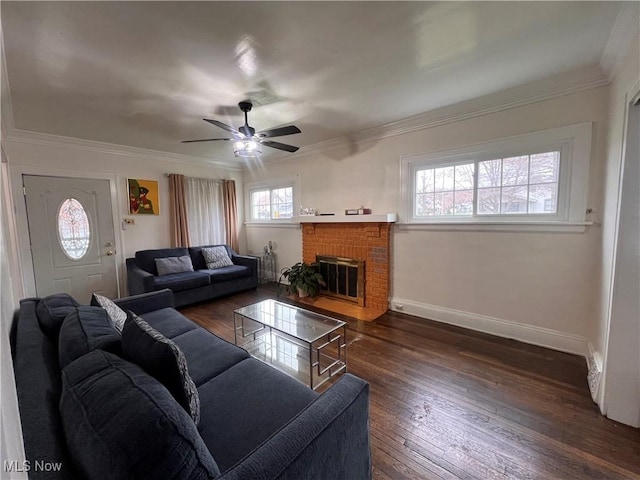 living area with crown molding, dark wood-style flooring, a fireplace, baseboards, and a ceiling fan