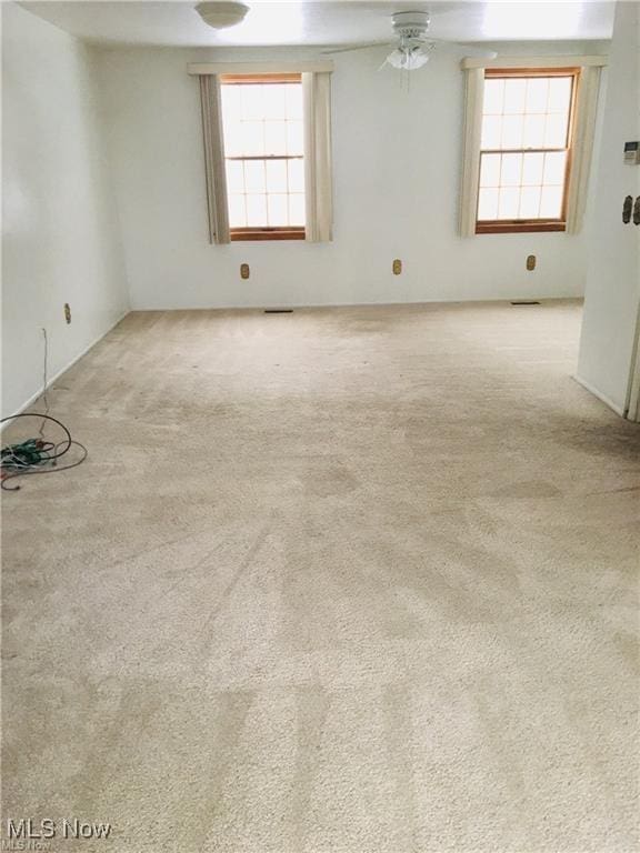 empty room featuring a healthy amount of sunlight, ceiling fan, carpet, and visible vents