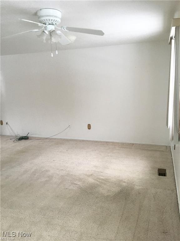 spare room with visible vents, carpet, and ceiling fan