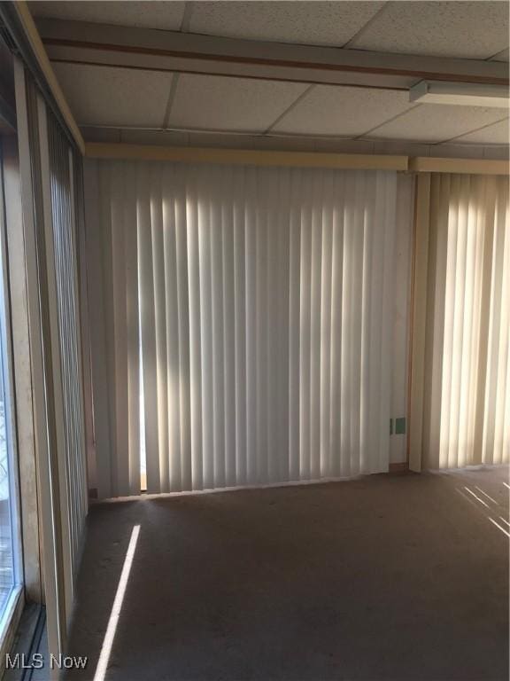 carpeted spare room featuring a paneled ceiling
