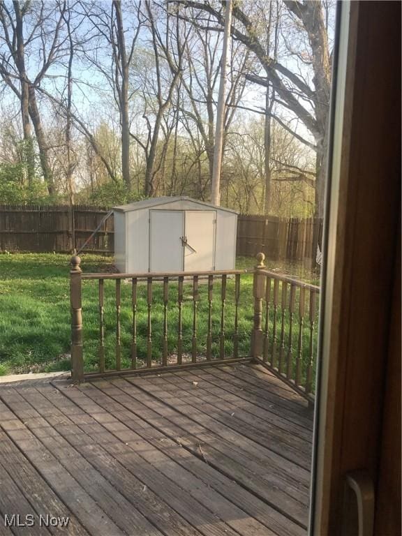 wooden terrace with a storage shed, a lawn, an outbuilding, and a fenced backyard