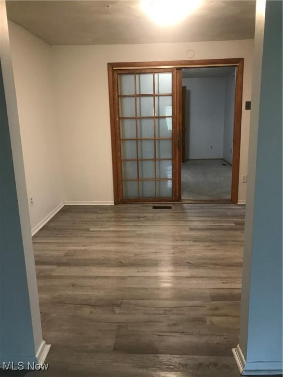 unfurnished room featuring baseboards, wood finished floors, and visible vents