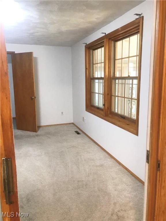 spare room featuring carpet floors, baseboards, and visible vents