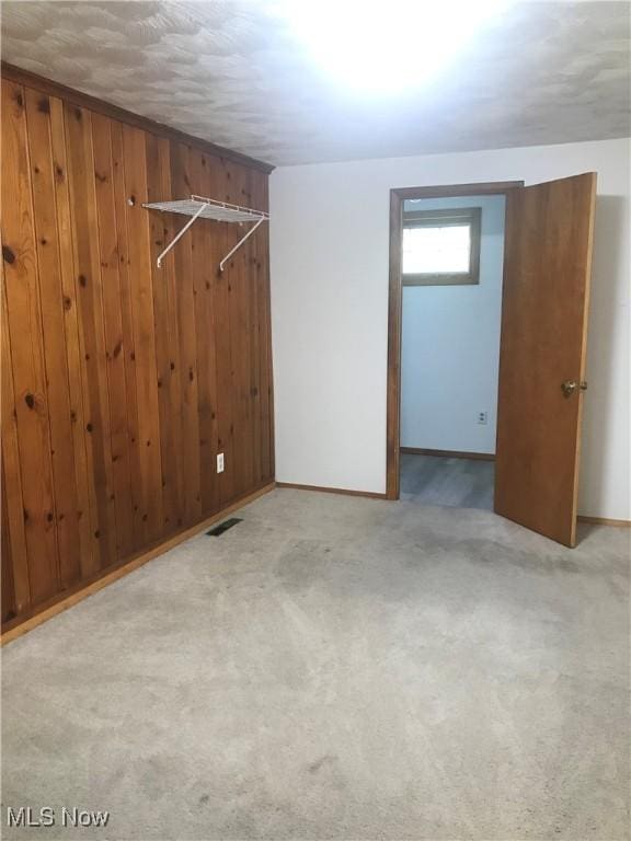 interior space featuring visible vents, wood walls, baseboards, and carpet floors