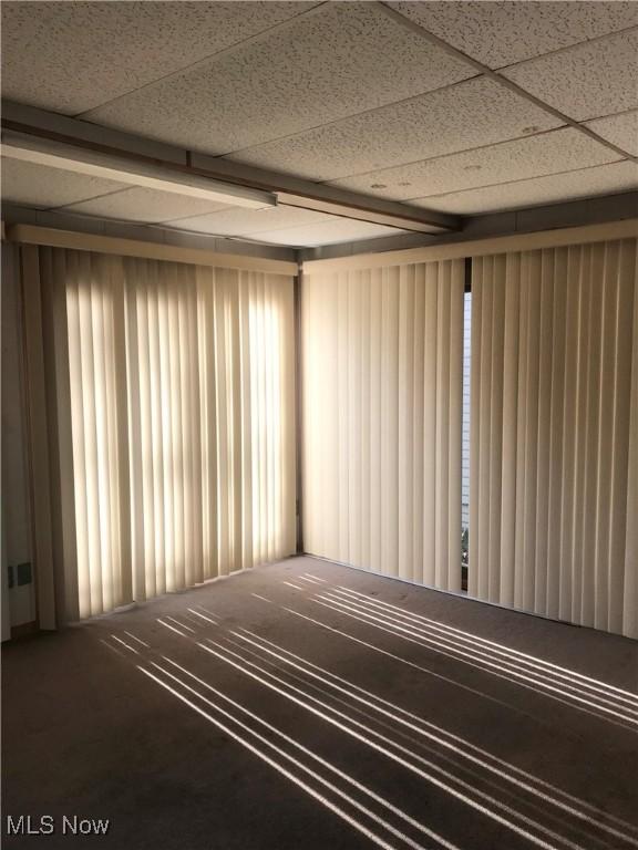 empty room with a drop ceiling and a wealth of natural light