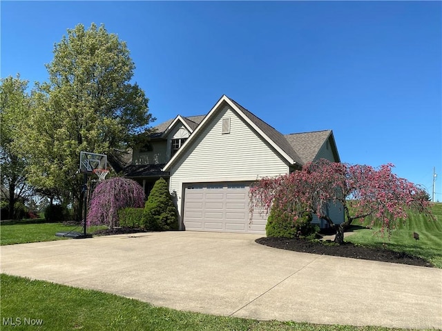 view of side of home with concrete driveway and an attached garage