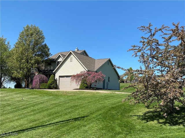 view of side of home with an attached garage and a lawn