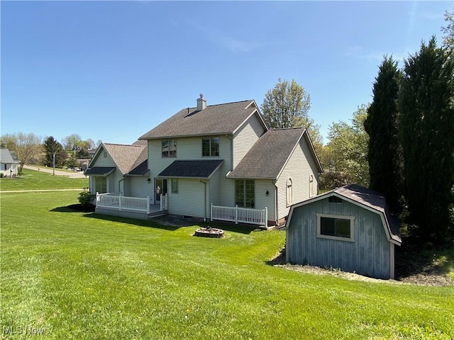 back of house with a storage shed, a wooden deck, a chimney, a lawn, and an outdoor structure