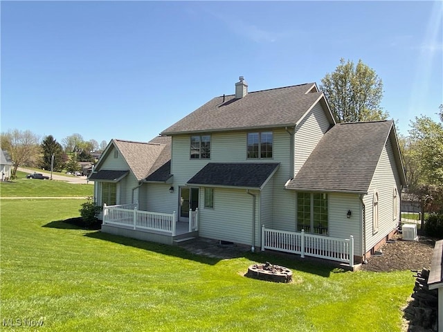 rear view of house with central air condition unit, a yard, a wooden deck, and a chimney