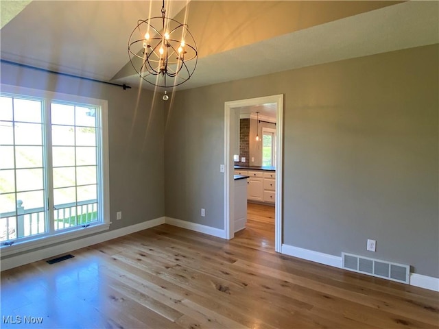 spare room featuring visible vents, light wood-style flooring, and baseboards