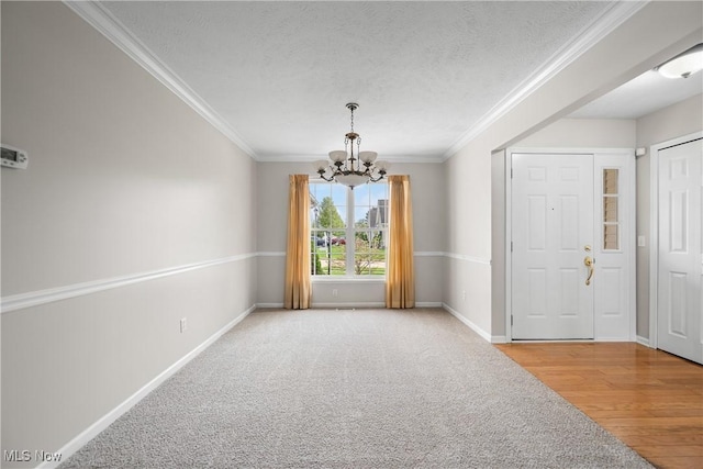 spare room featuring crown molding, a textured ceiling, baseboards, and a chandelier