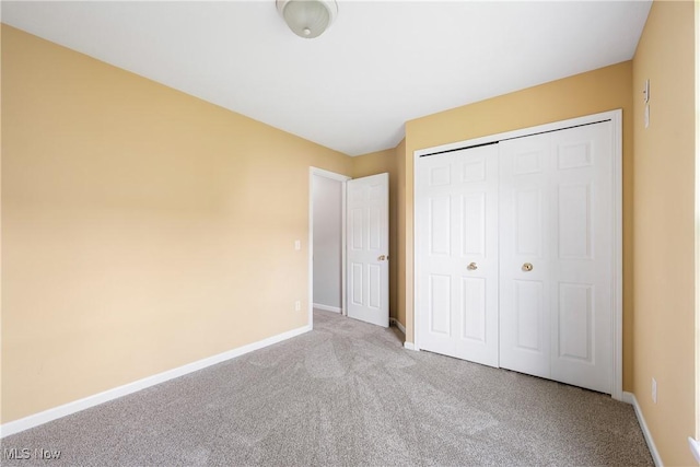 unfurnished bedroom featuring baseboards, carpet, and a closet