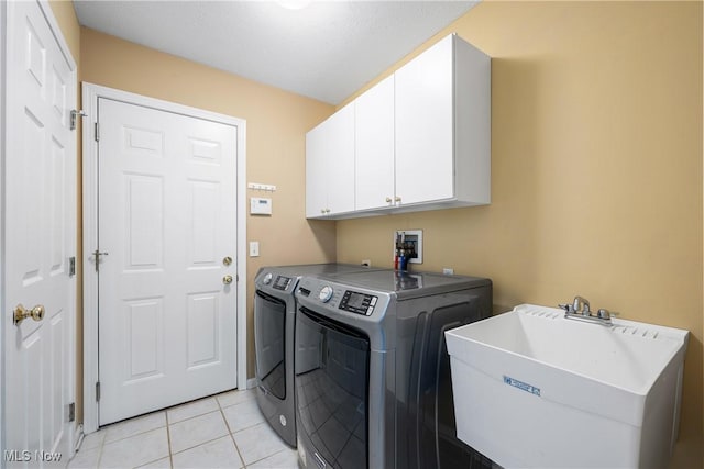 clothes washing area featuring a sink, cabinet space, light tile patterned floors, and washing machine and clothes dryer