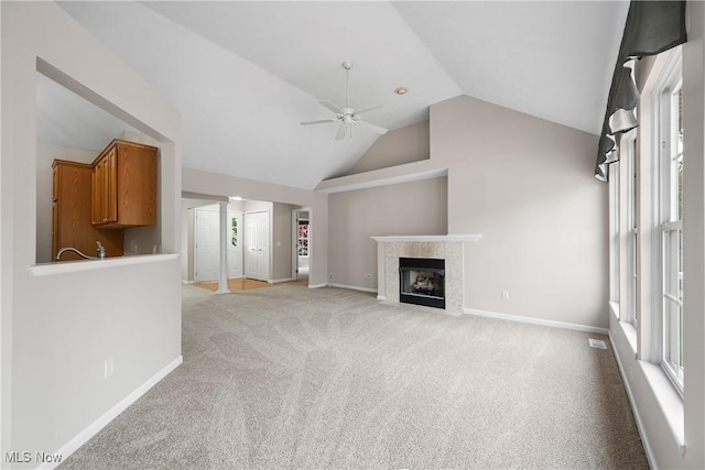 unfurnished living room featuring ceiling fan, light colored carpet, a fireplace, vaulted ceiling, and baseboards