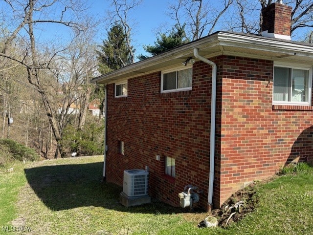 view of property exterior featuring central air condition unit, a chimney, a lawn, and brick siding
