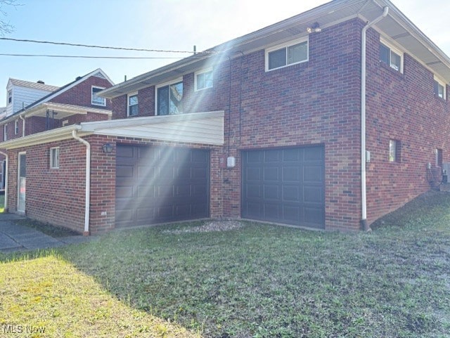 rear view of house with brick siding, a garage, and a lawn
