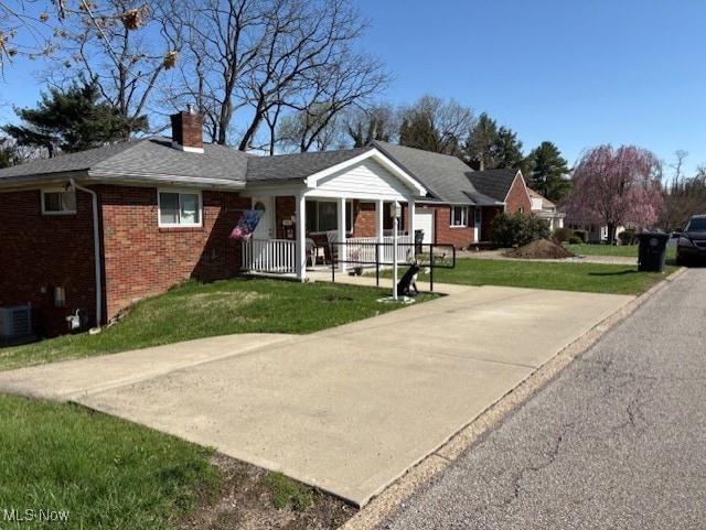 single story home featuring a front lawn, a chimney, brick siding, a porch, and central air condition unit