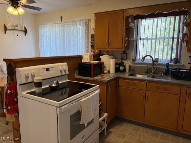 kitchen with ceiling fan, brown cabinets, a sink, light tile patterned floors, and white electric range oven