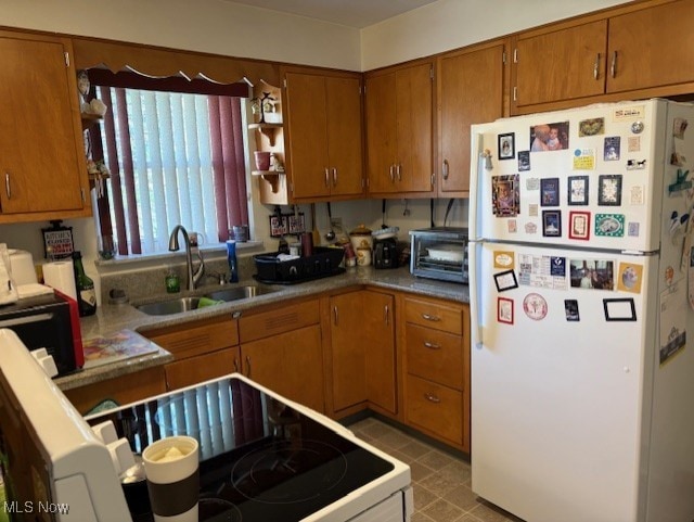 kitchen with brown cabinetry, range with electric cooktop, open shelves, a sink, and freestanding refrigerator