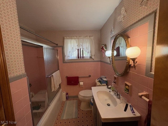 bathroom with toilet, wallpapered walls, tile walls, and vanity