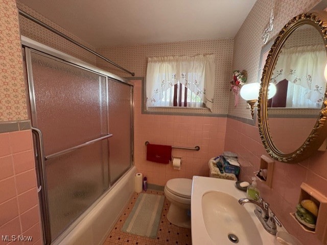 full bath with a sink, tile walls, tile patterned floors, and wallpapered walls