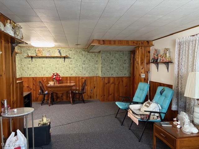 carpeted dining area featuring wainscoting and wood walls