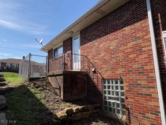 view of side of home with brick siding and fence