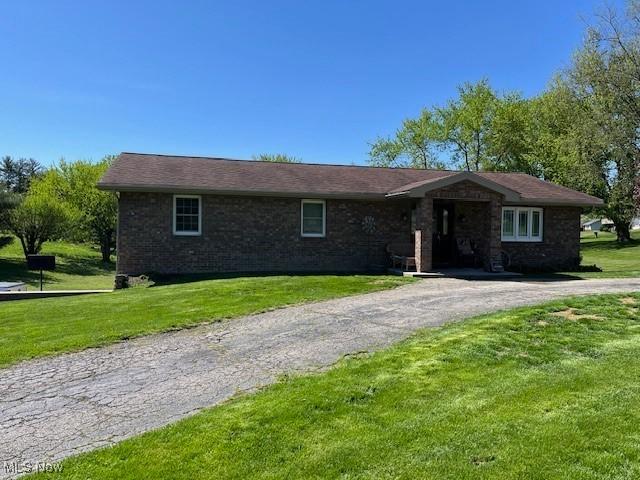 ranch-style home featuring brick siding, driveway, and a front yard